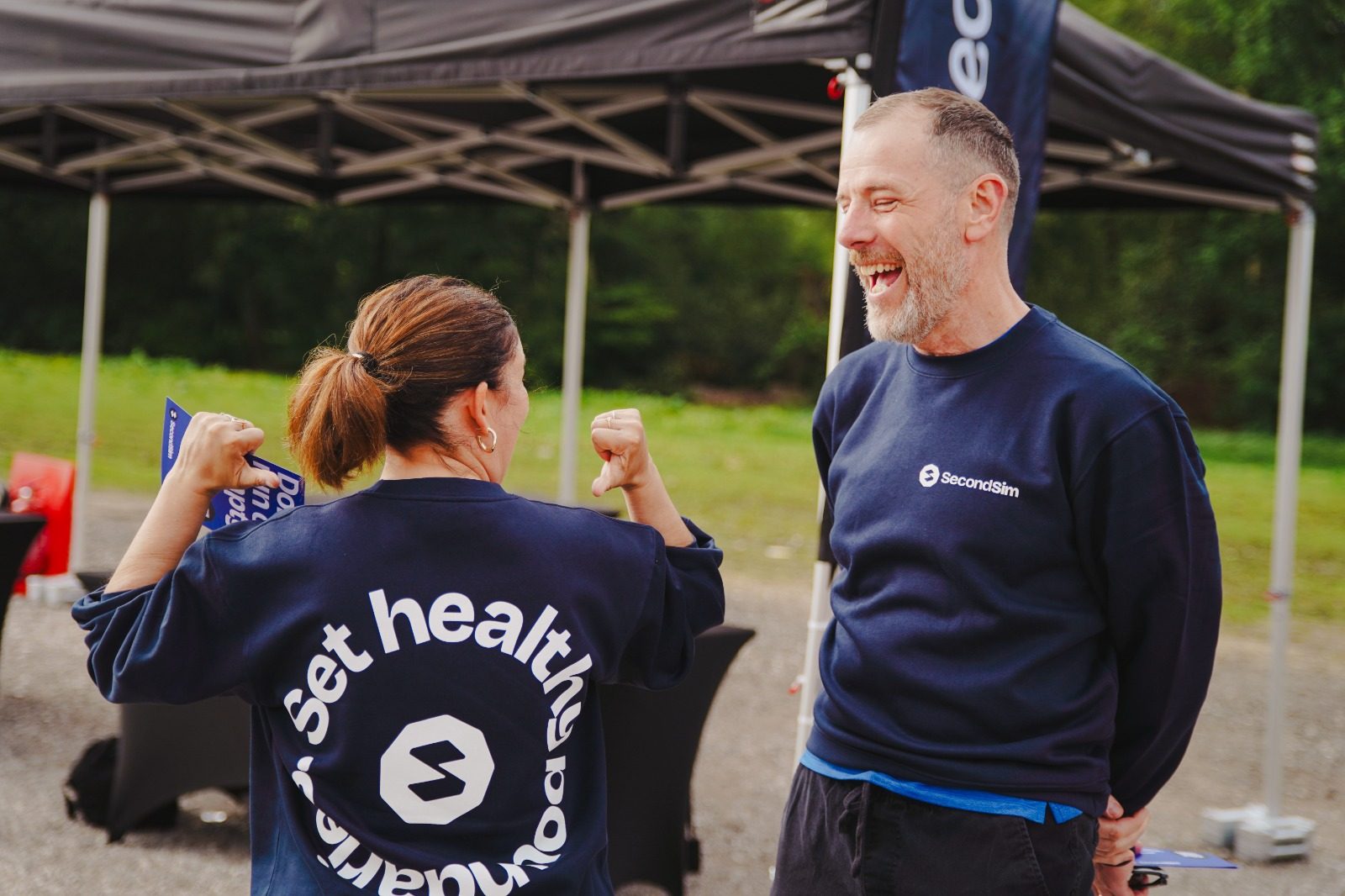 Two Solo Squad members in SecondSim sweatshirts laughing at a Greater Manchester Wellbeing Series event